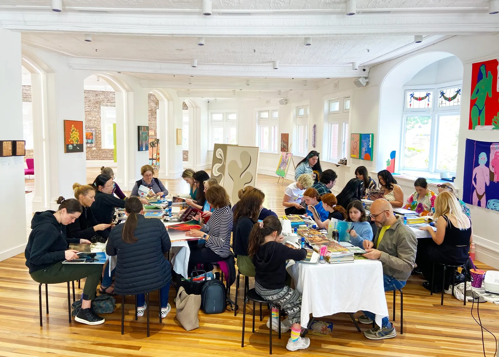 A large group working at long tables during a Sydney Collage Society workshop